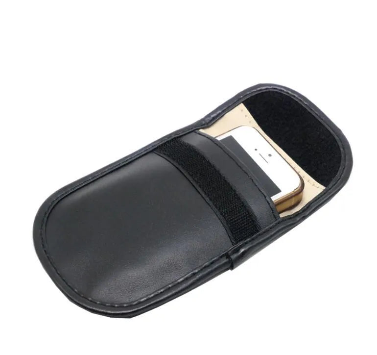 Black microfiber Faraday cage pouch for blocking car key and RFID card signals on a table.