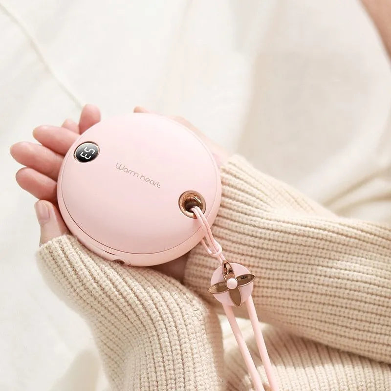 Green 5000mAh power bank hand warmer with digital display shown next to its charging cable.