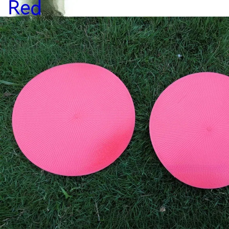 Soft yellow TPE football training target pad flat on grass, 23cm diameter.