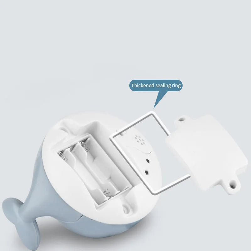 Whale-shaped baby bath toy with automatic water spray, flashing lights, and music on a base.