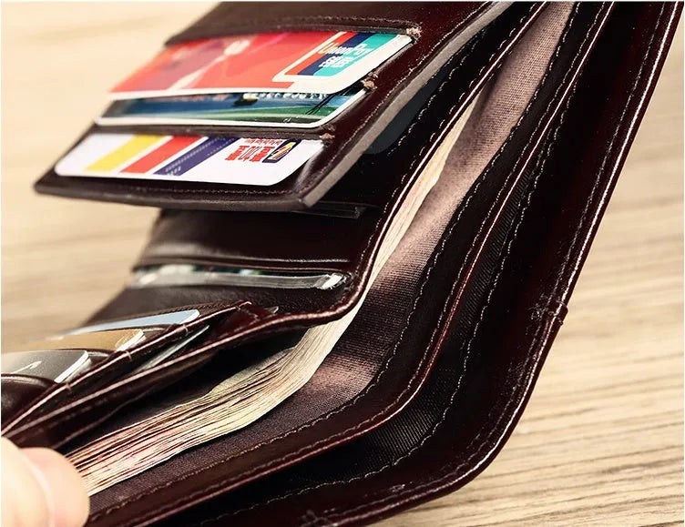 Men's black full-grain leather bifold wallet showing open interior with card slots and an exterior zippered coin pouch.