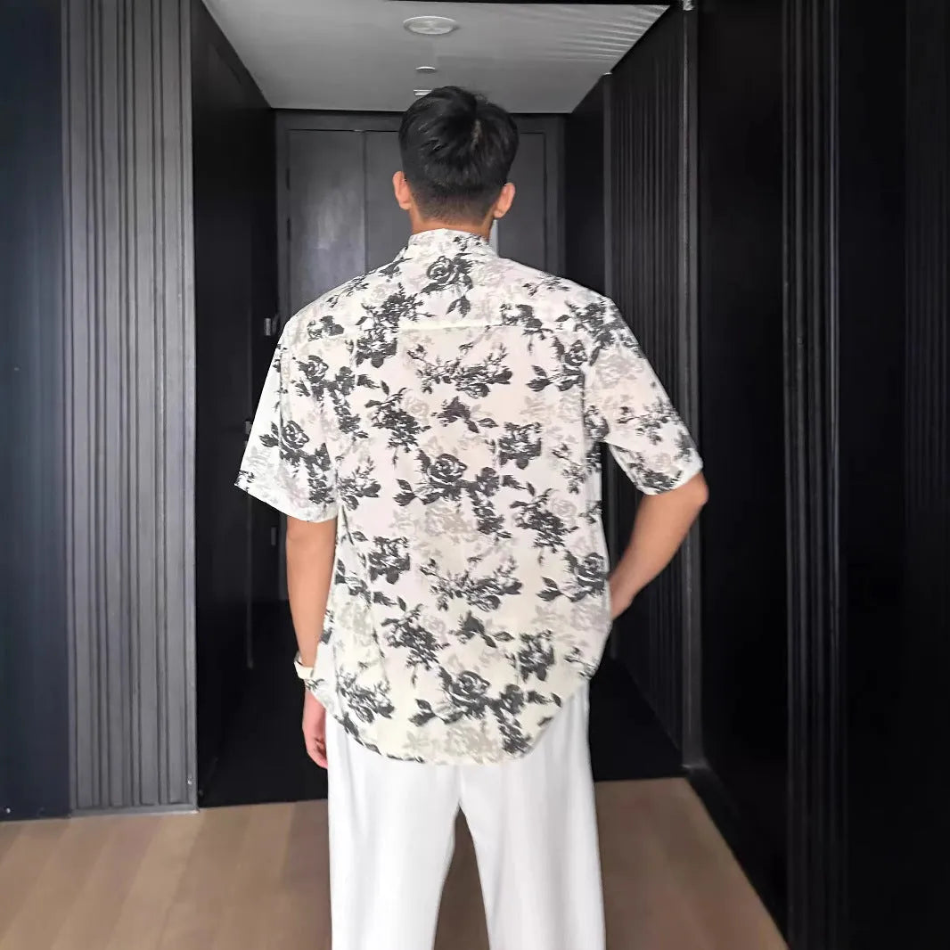 Loose fit floral printed short sleeve shirt in black, hanging on a hanger.
