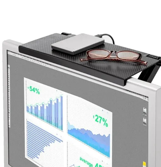 Black adjustable screen top shelf on a desktop monitor holding a streaming device and remote