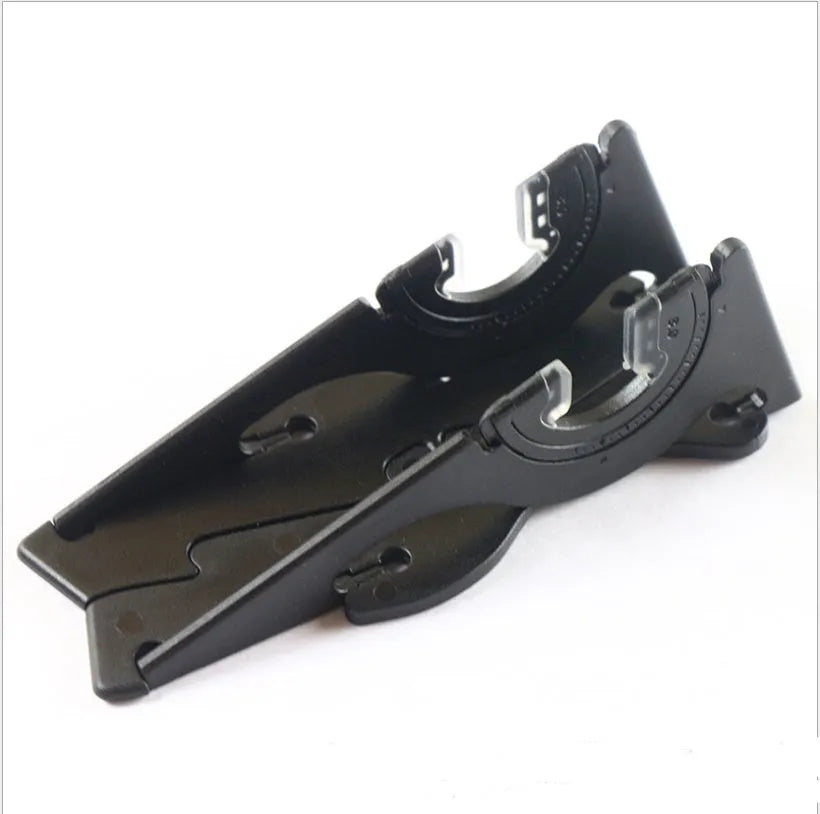 A black plastic card-type mobile phone holder standing upright on a wooden desk.
