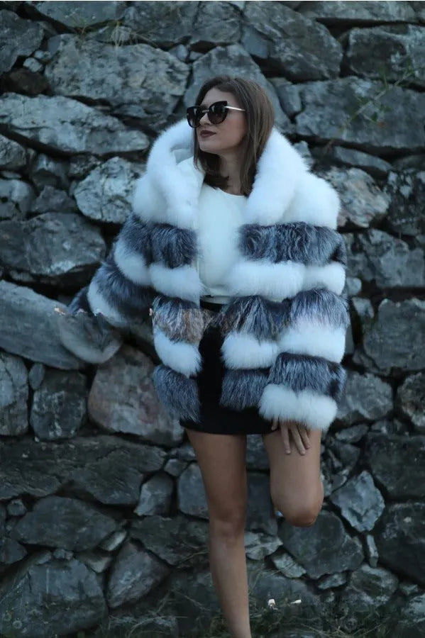 A woman modelling a loose-fitting, hooded artificial fur coat in a street fashion style.