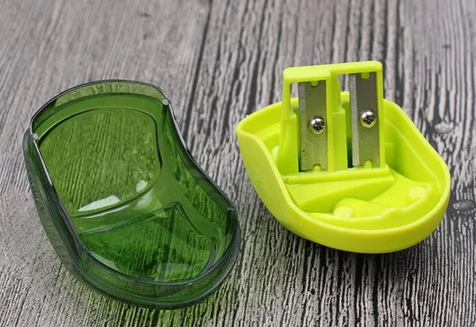 Single hole manual pencil sharpener in a random colour on a desk, showing its closed design.