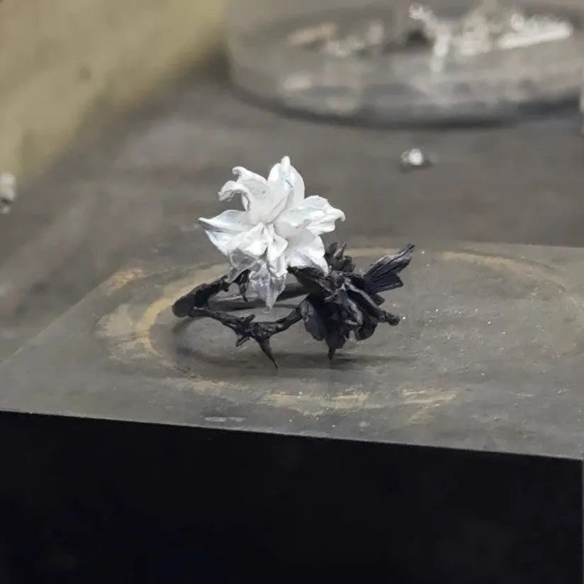 Open mouth copper ring with white and black colour separation and lily motif on a plain background