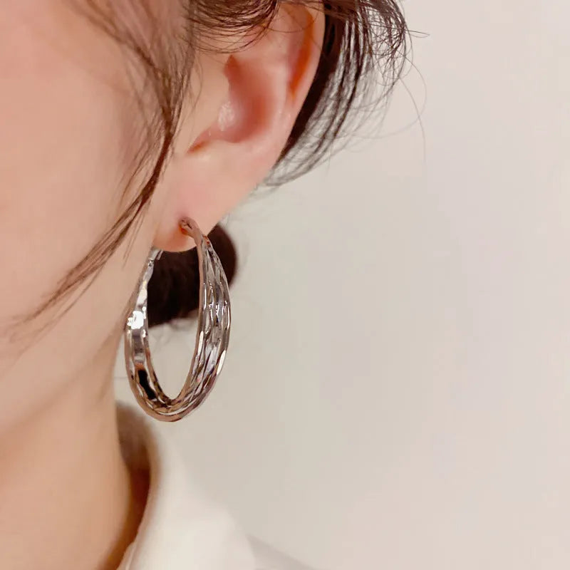 Gold and silver twisted metal earrings with copper body, round geometric shape, and silver needle for women.