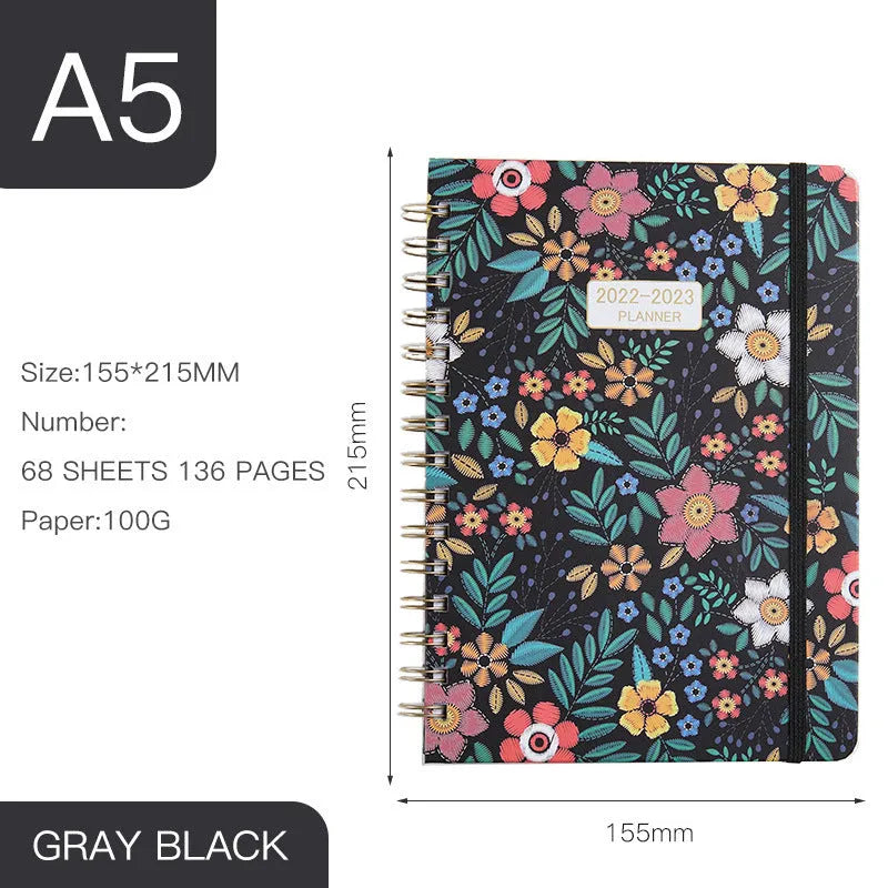 A5 spiral notebook with colourful floral cover design, lying open on a table.