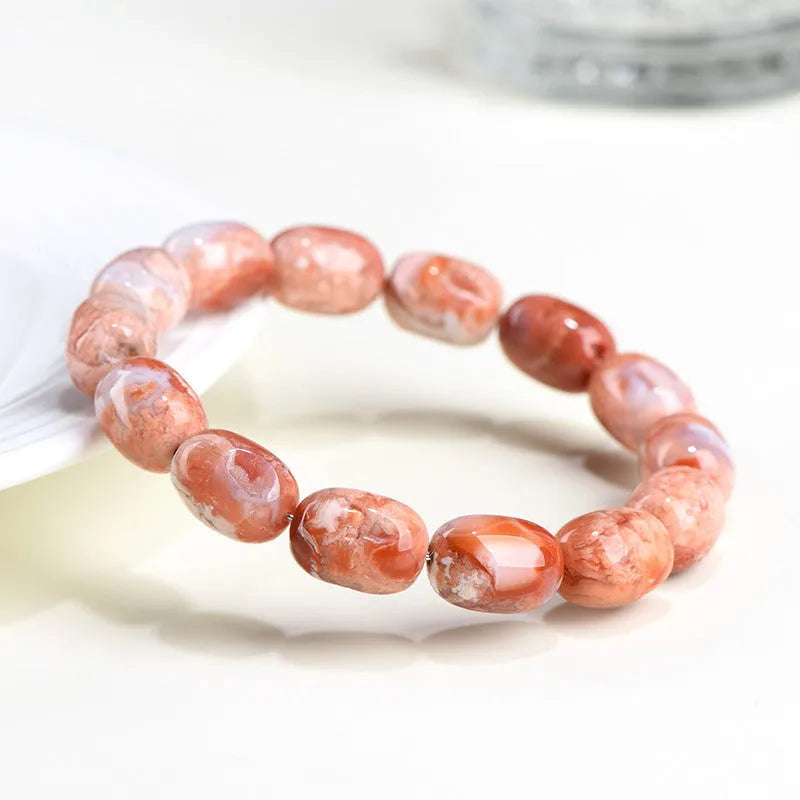 Natural cherry agate barrel bead bracelet with Ruyi charm on a wrist.