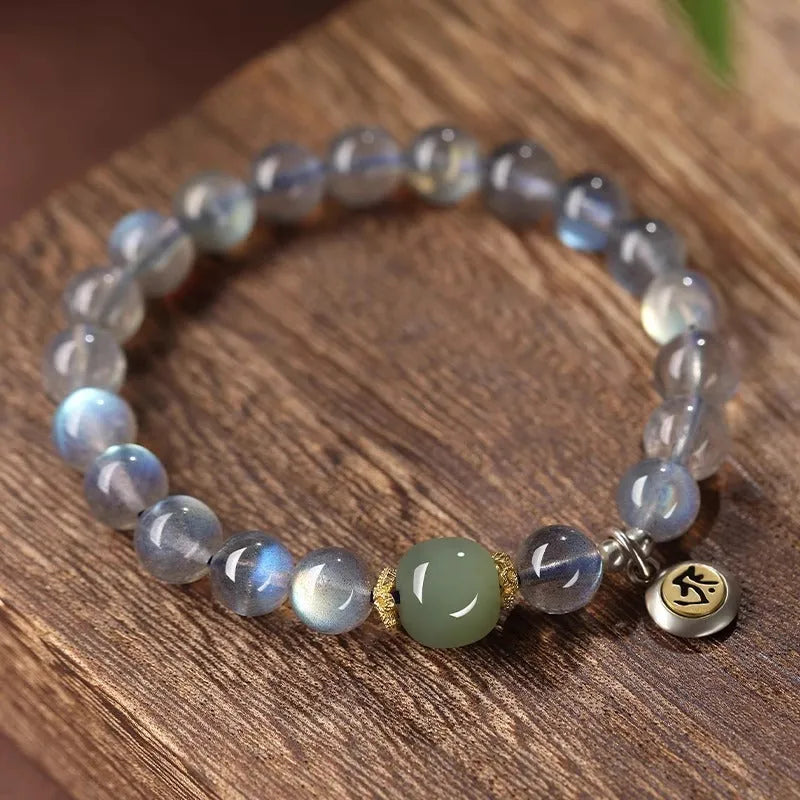 Moonstone bracelet with 8mm beads and a silver Guanyin mouse zodiac charm on a black background.