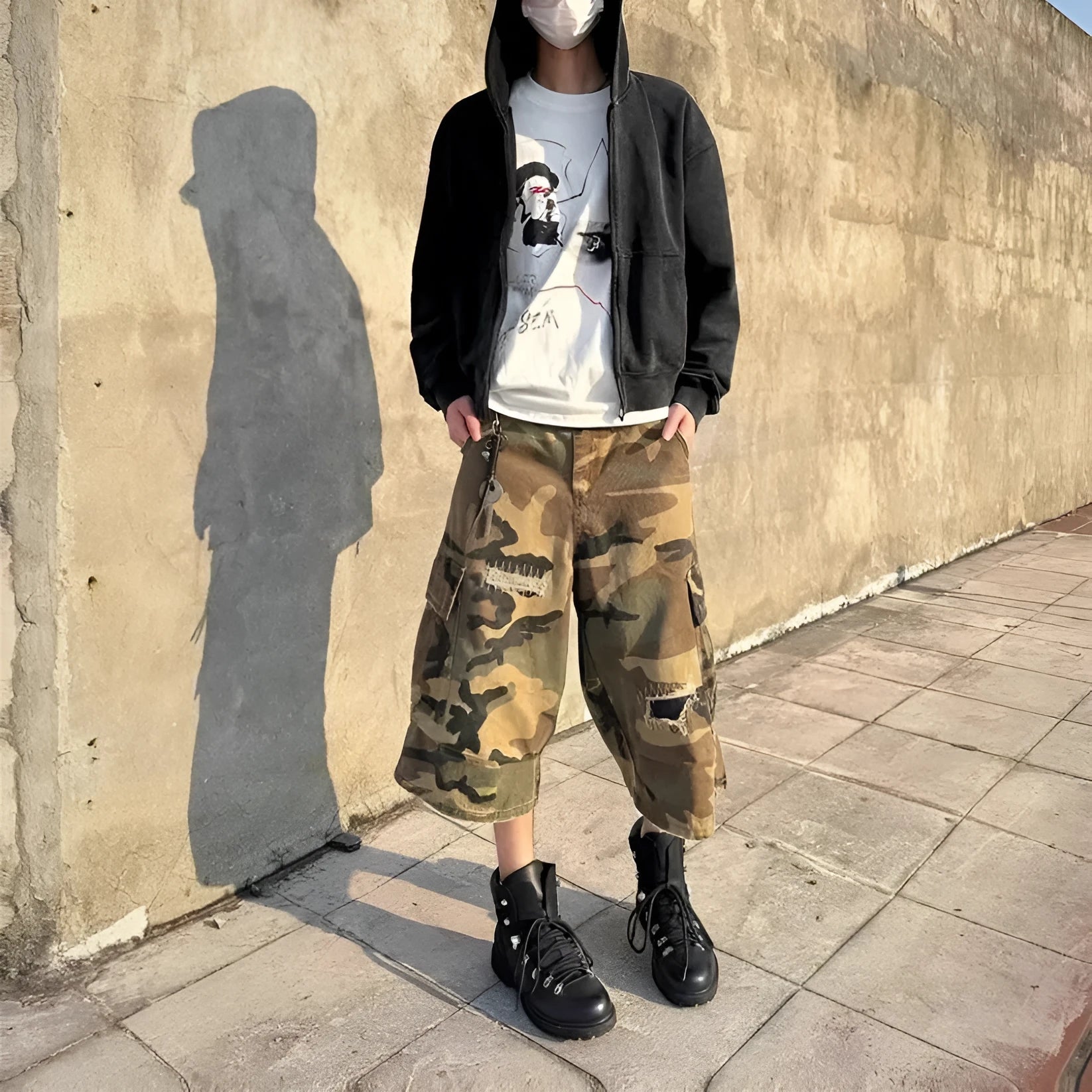 Men's loose-fit camouflage cropped jeans with ripped details and patches on a straight leg.