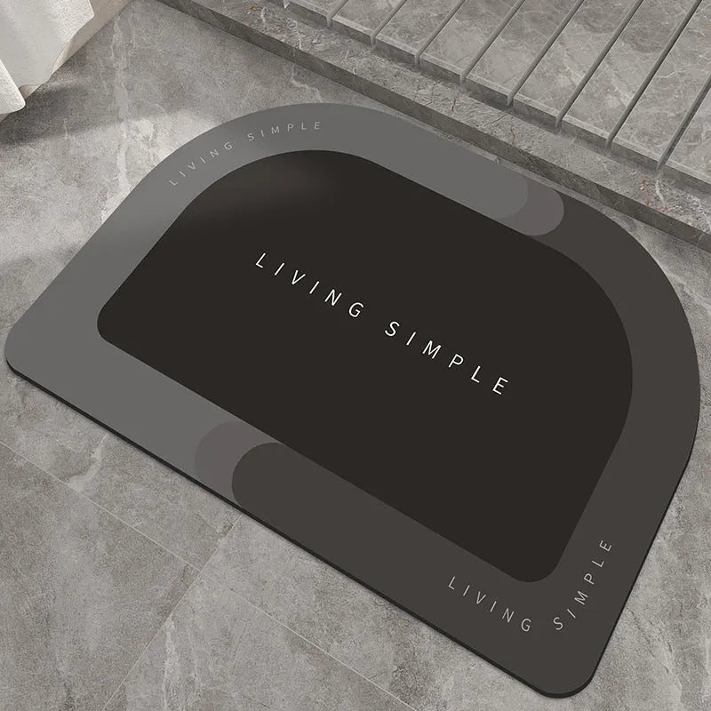 Oval grey polyester door mat with textured rubber non-slip backing on a wooden floor.