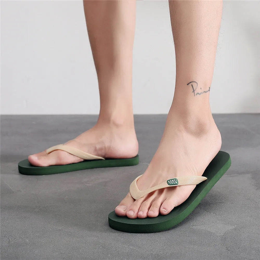 Men's black flip-flops with a textured rubber sole and a lightweight EVA upper on a sandy beach.