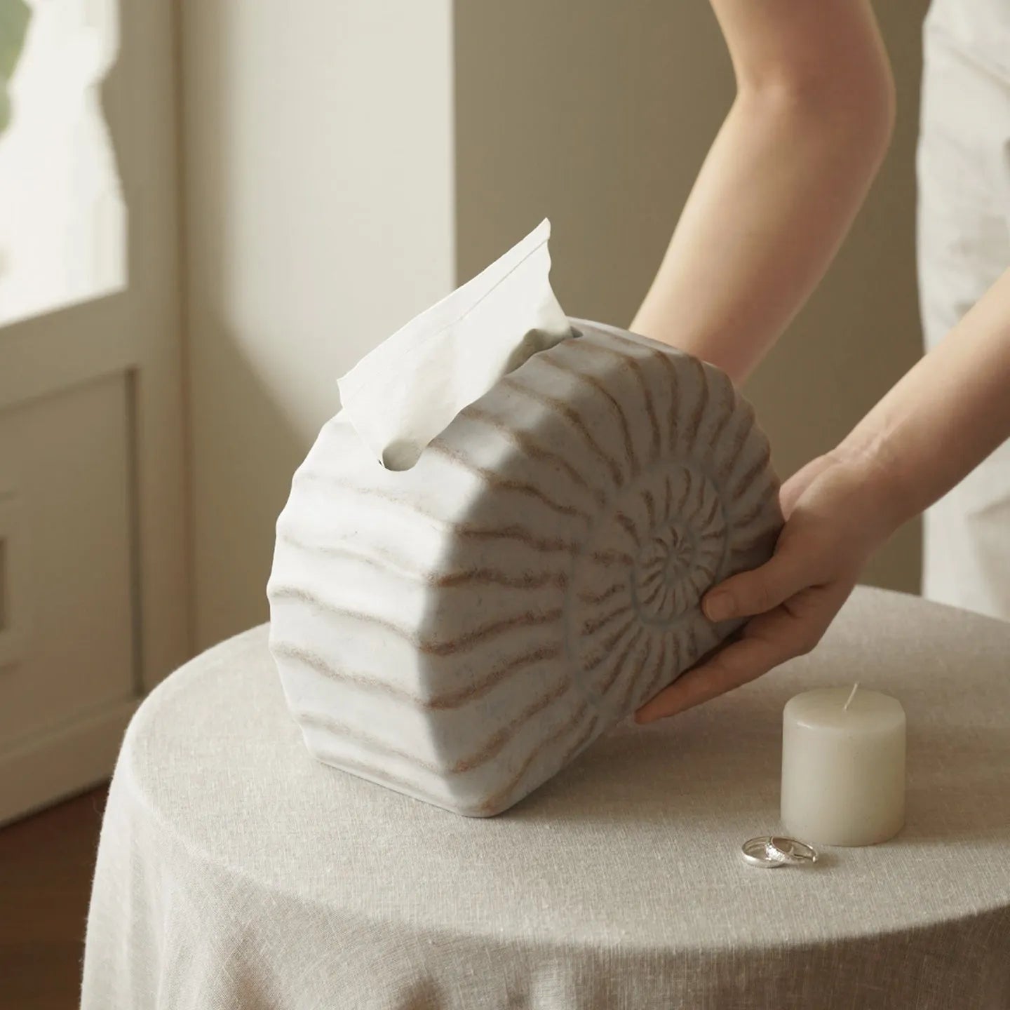 White conch ramble shell design resin tissue box holder on a table.