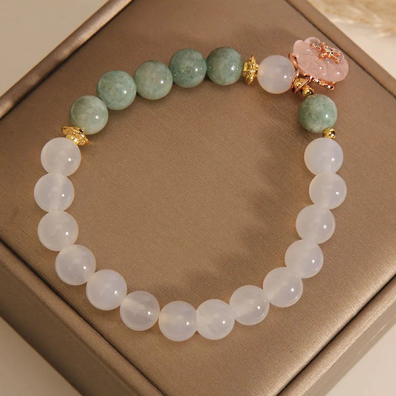 White agate jade bracelet with floral shape on a casual model wrist.
