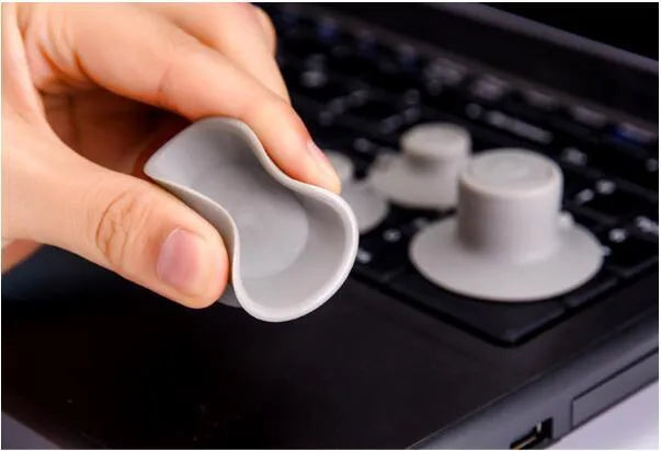 Four grey plastic laptop cooling pads, two large and two small, placed under a silver laptop on a wooden desk.