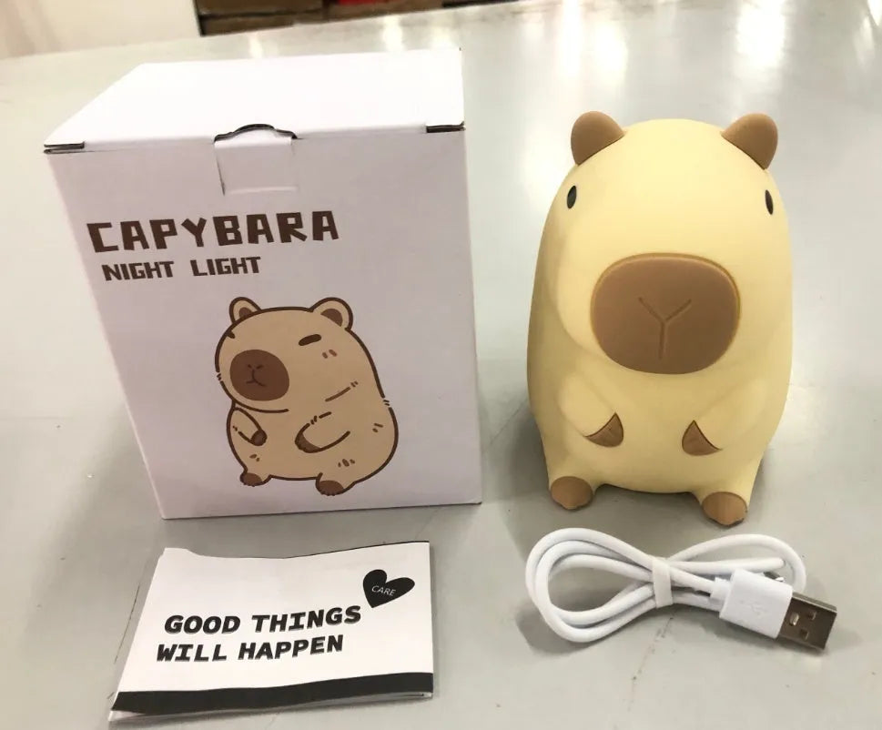 Small capybara-shaped night lamp in silicone and plastic, shown with USB cable.