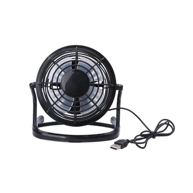 Mini black USB desk fan with adjustable head on a desk next to a laptop.