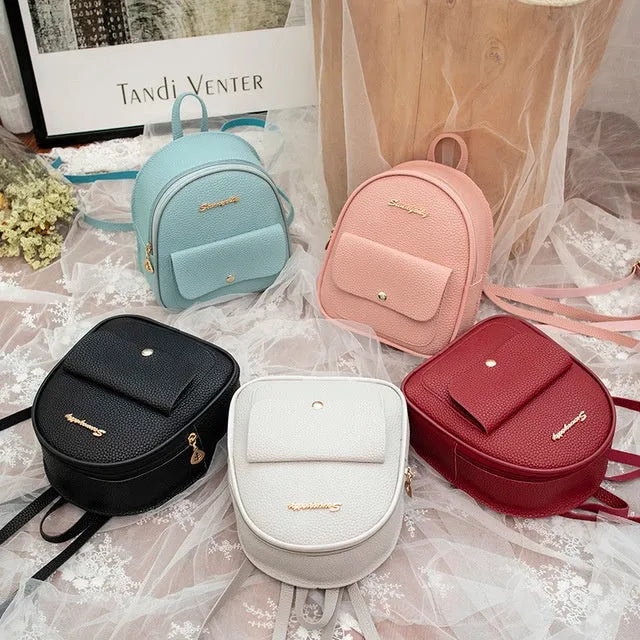 Small black PU women's backpack worn on shoulder, showing zip closure and compact size.