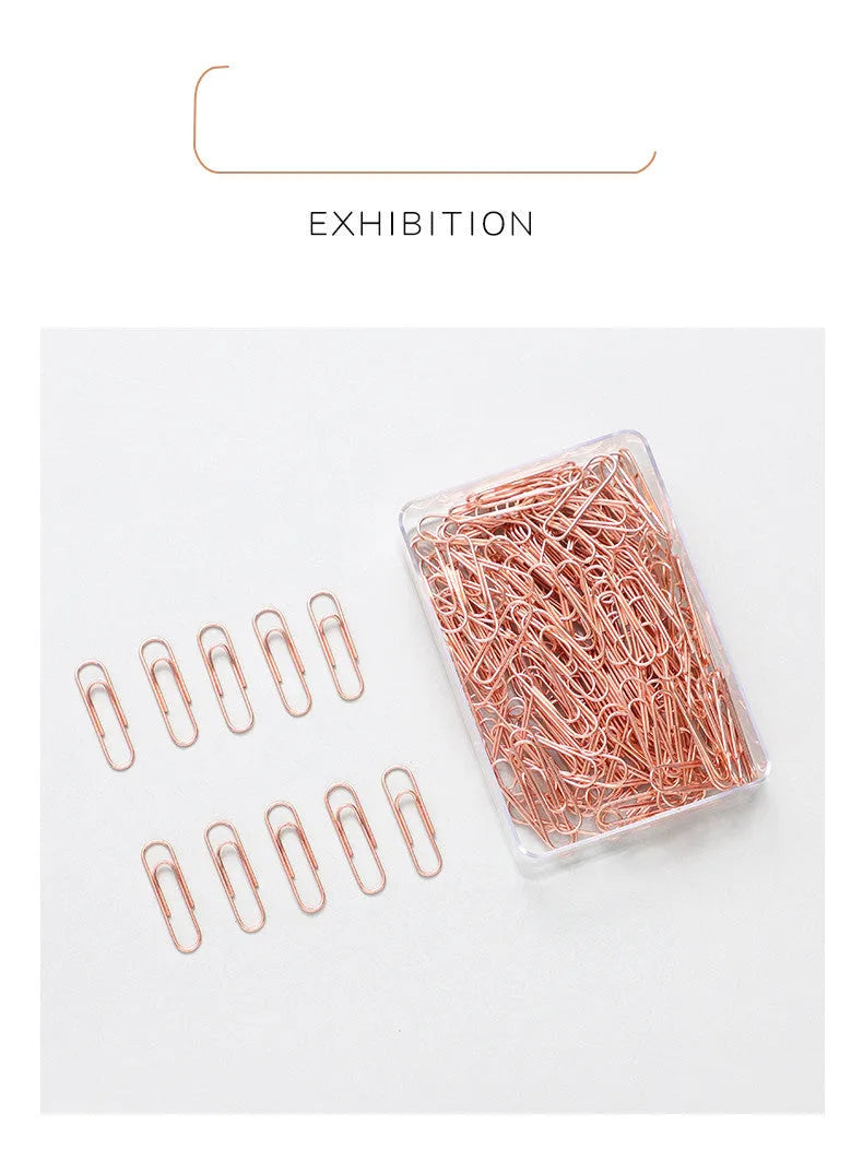 100 rose gold coloured heart-shaped metal paper clips in a box.