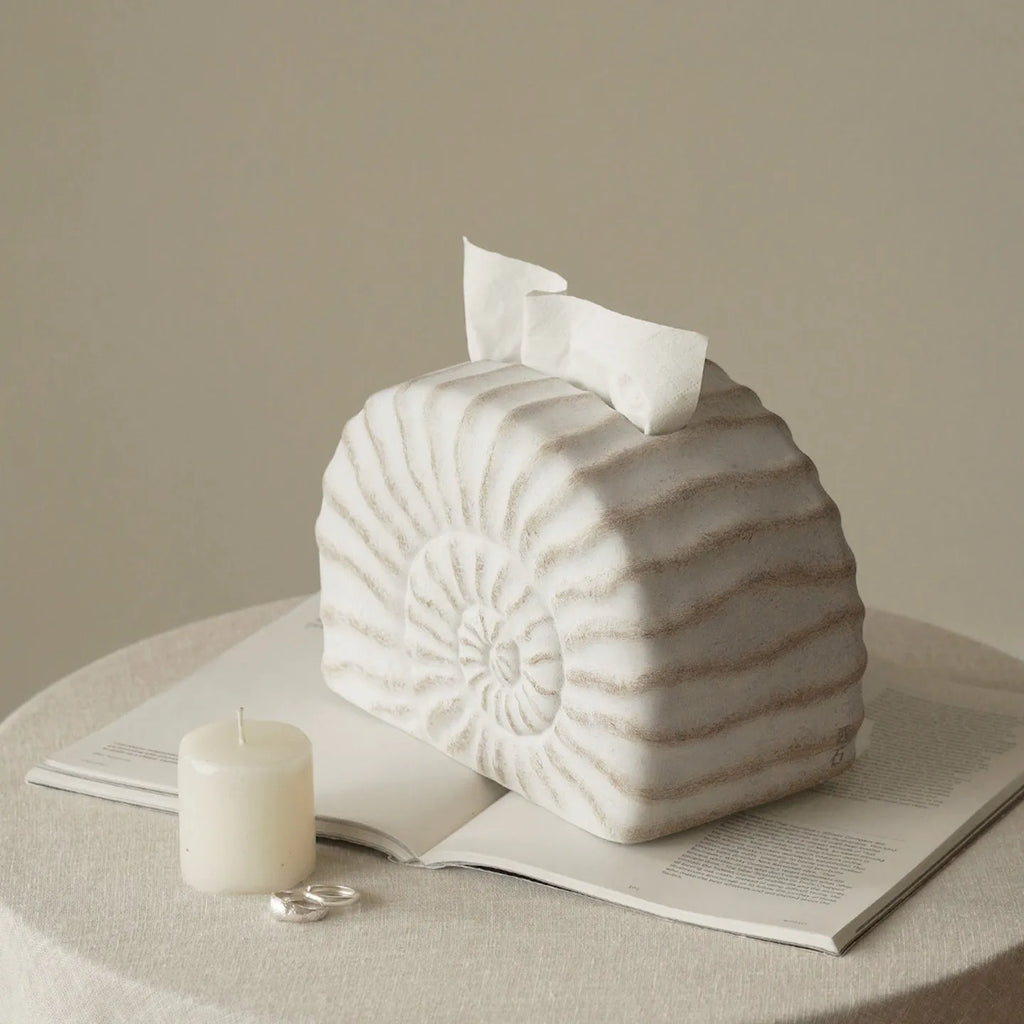 White conch ramble shell design resin tissue box holder on a table.