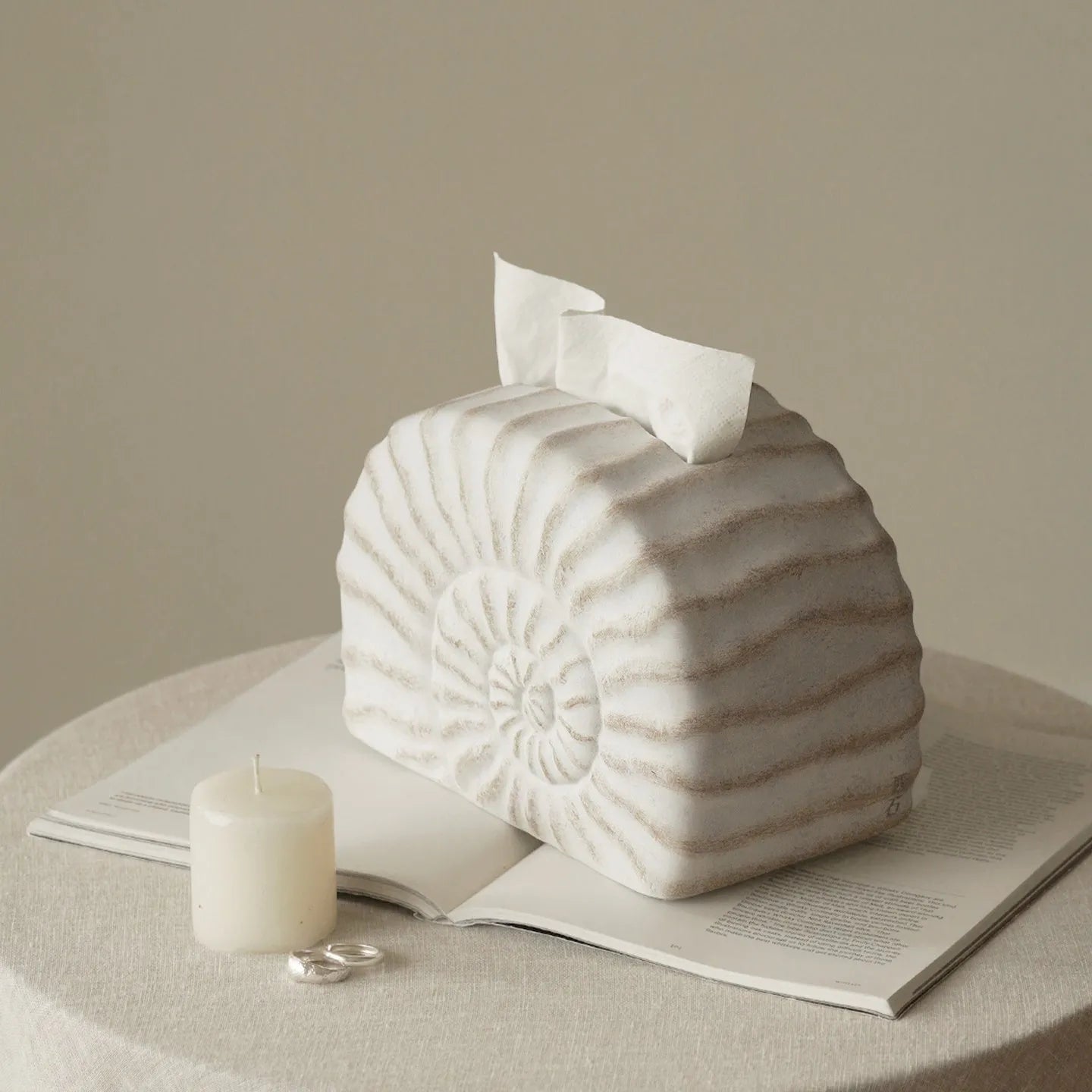 White conch ramble shell design resin tissue box holder on a table.