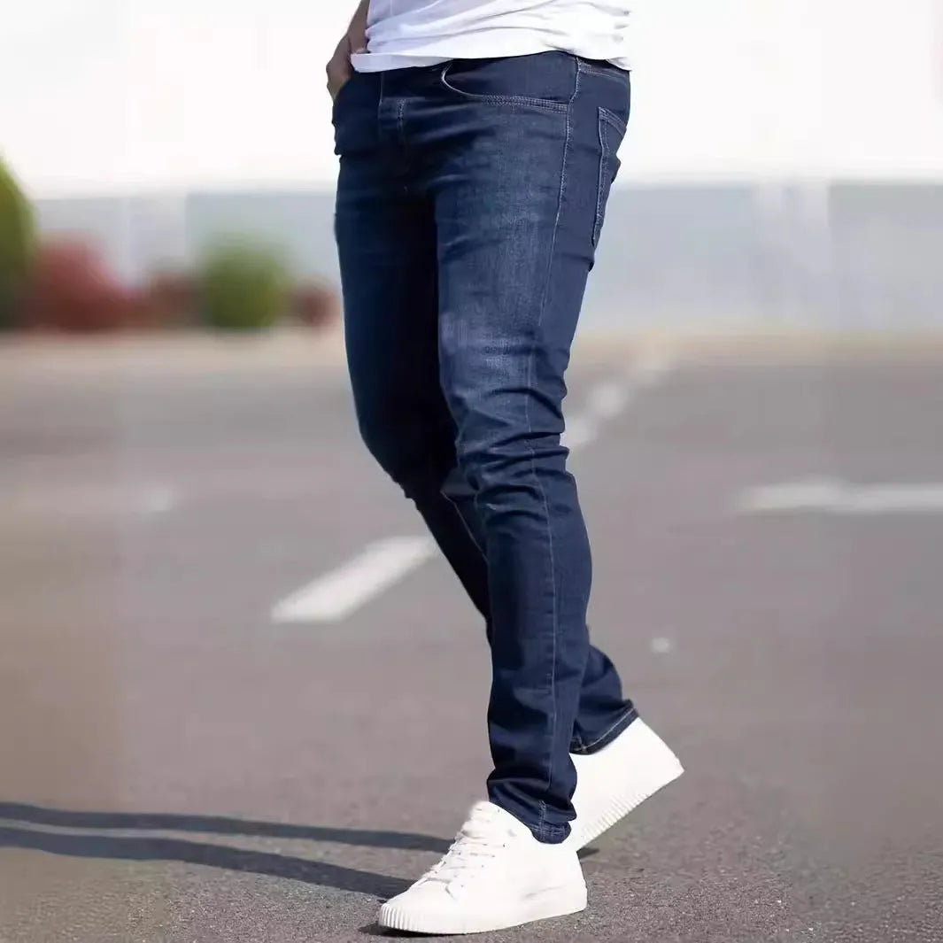 Men's dark blue skinny fit cotton jeans with a mid-rise waist and zipper fly on a plain background.
