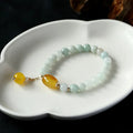 Women's ethnic bracelet with hanging red agate tassel on a gold chain.