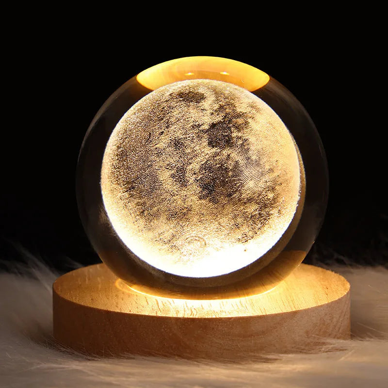 Clear crystal ball LED night light showing a 3D galaxy or planet design, lit from within on a table.