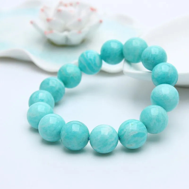 Natural blue-green amazonite gemstone bracelet with round polished beads on a white background.