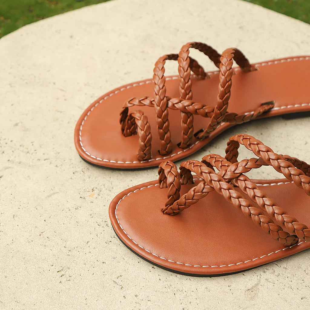 Women's brown woven flat sandals with a clip-toe strap and adjustable buckle on a neutral background.