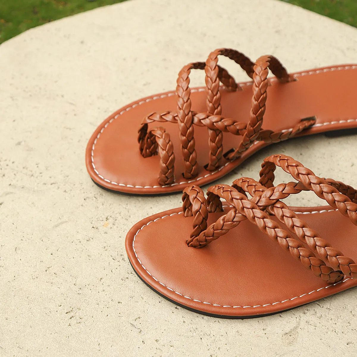 Women's brown woven flat sandals with a clip-toe strap and adjustable buckle on a neutral background.