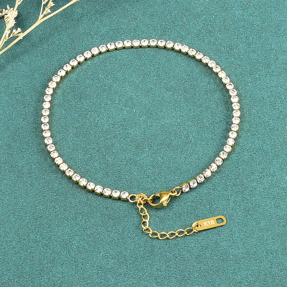 Gold titanium steel anklet with small fruit-shaped pendant and adjustable tail chain on bare ankle