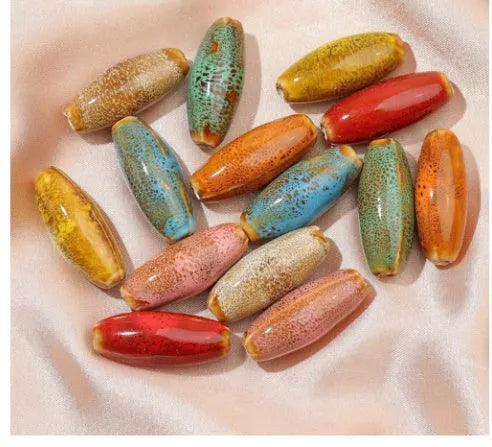 Assorted high-temperature fired ceramic bullet beads in pink, yellow, blue, red, coffee, green, orange, and mixed glaze colours.