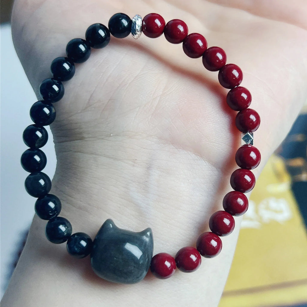 Obsidian crystal cat bracelet with colourful woven string band on a wrist.