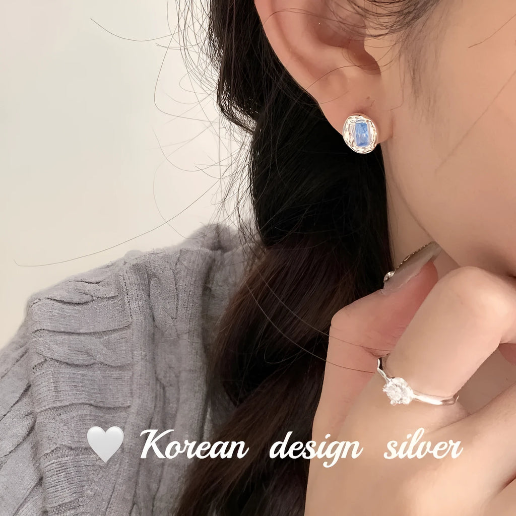 Silver geometric earrings with oval blue diamond wrapped in heart motif