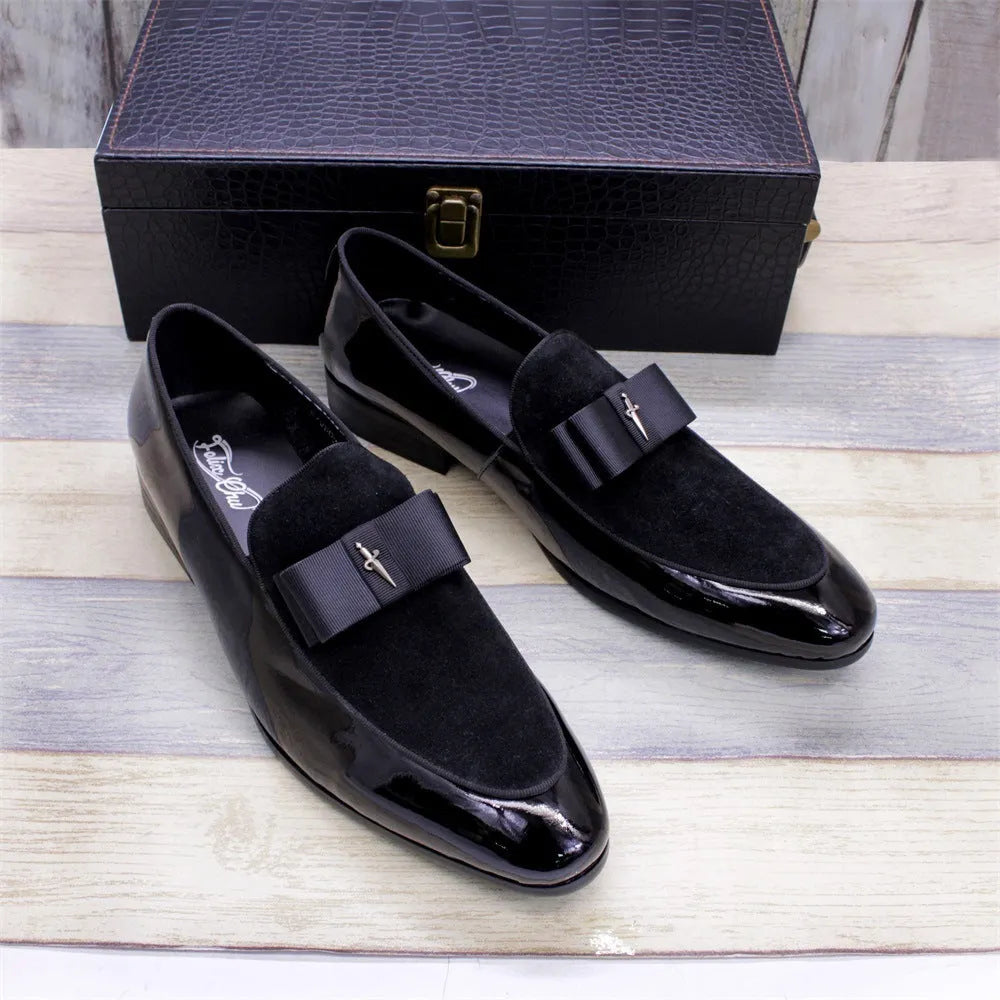 Men's black patent leather tassel loafers with a matte toe, shown on a wooden floor.