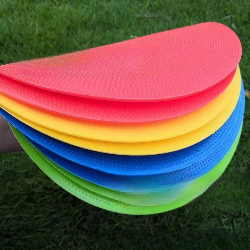 Soft yellow TPE football training target pad flat on grass, 23cm diameter.
