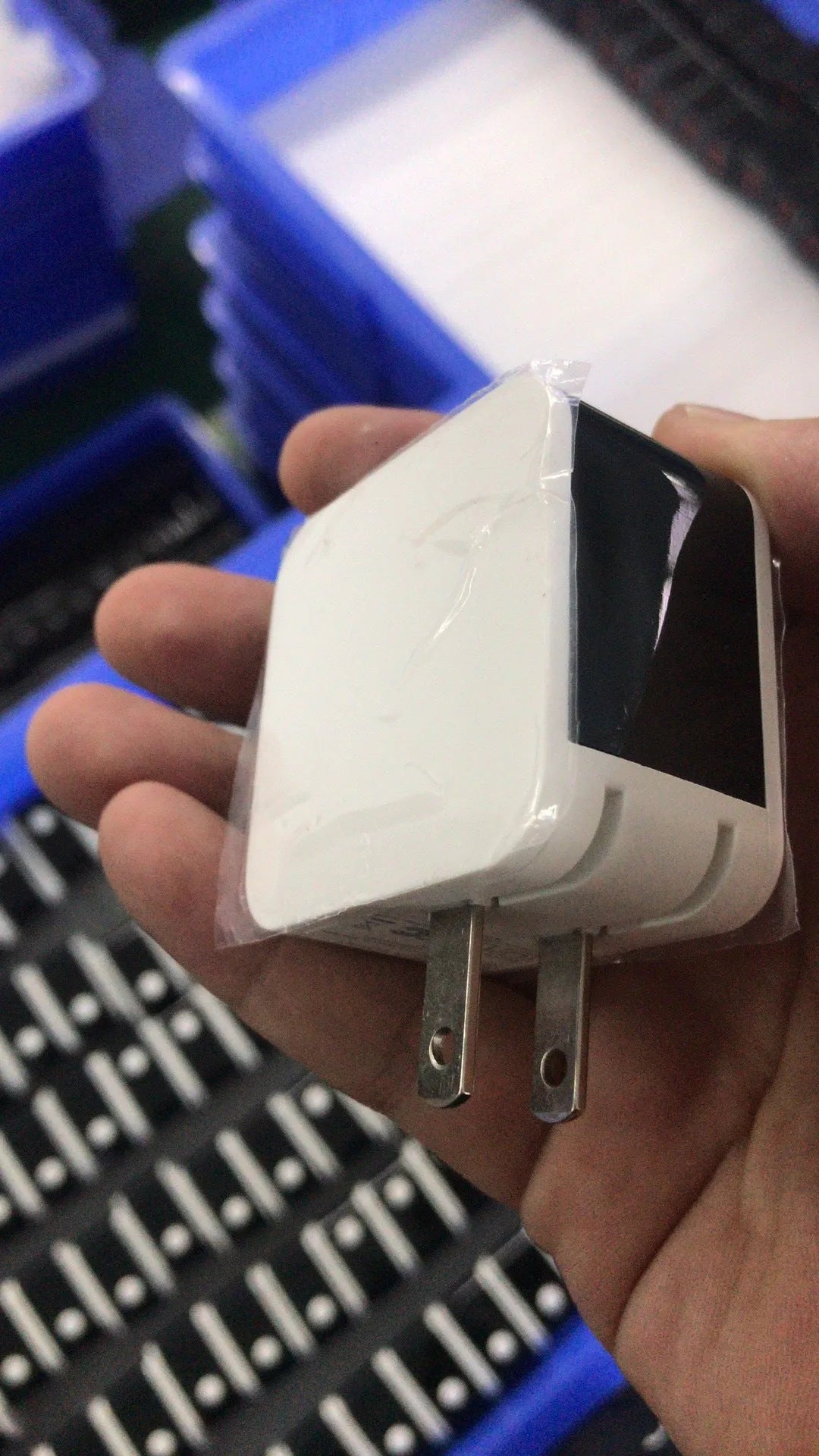 A black dual USB travel charger with a digital display showing '5V', plugged into a UK wall socket.