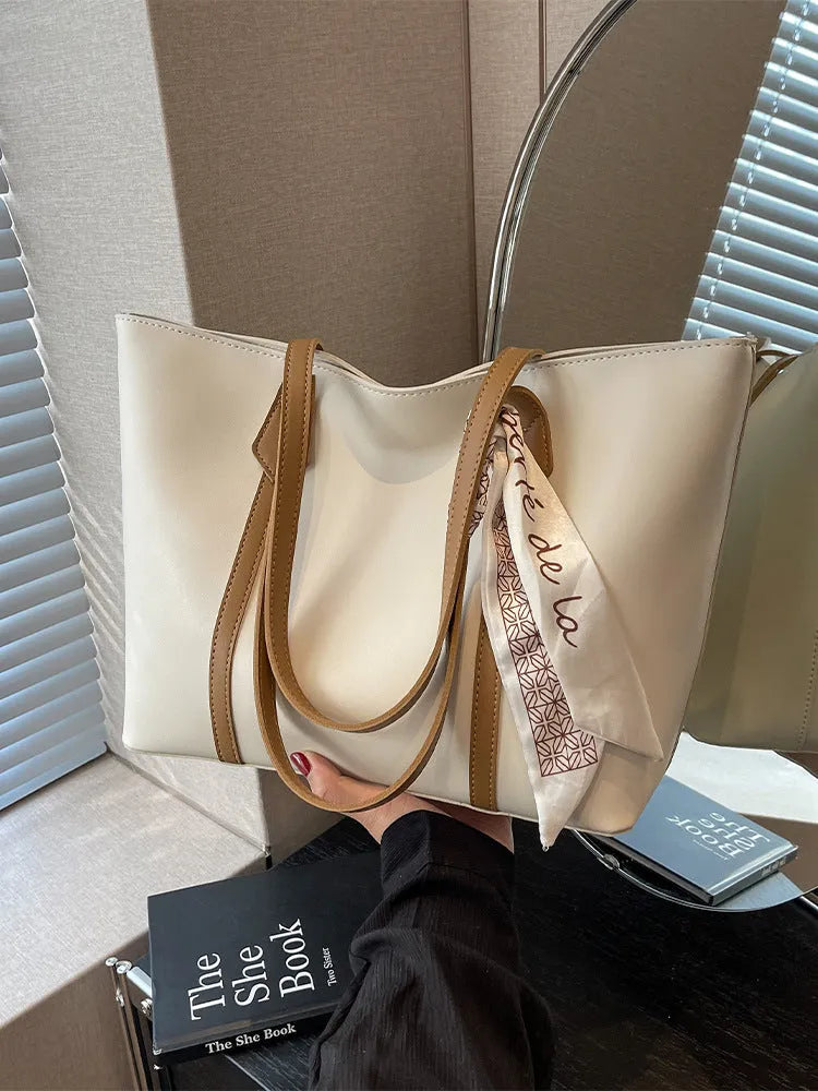 Large soft crossbody tote bag in bucket design showing colour options and internal zipped pocket