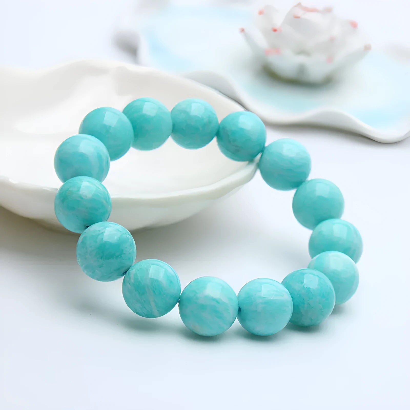 Natural blue-green amazonite gemstone bracelet with round polished beads on a white background.