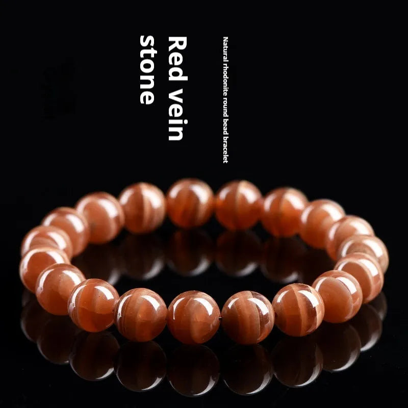 Natural Old Mine Rhodochrosite round bead bracelet with geometric design on wrist.