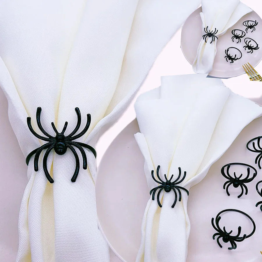 Set of six black alloy Halloween napkin rings with detailed spider design on a table setting.