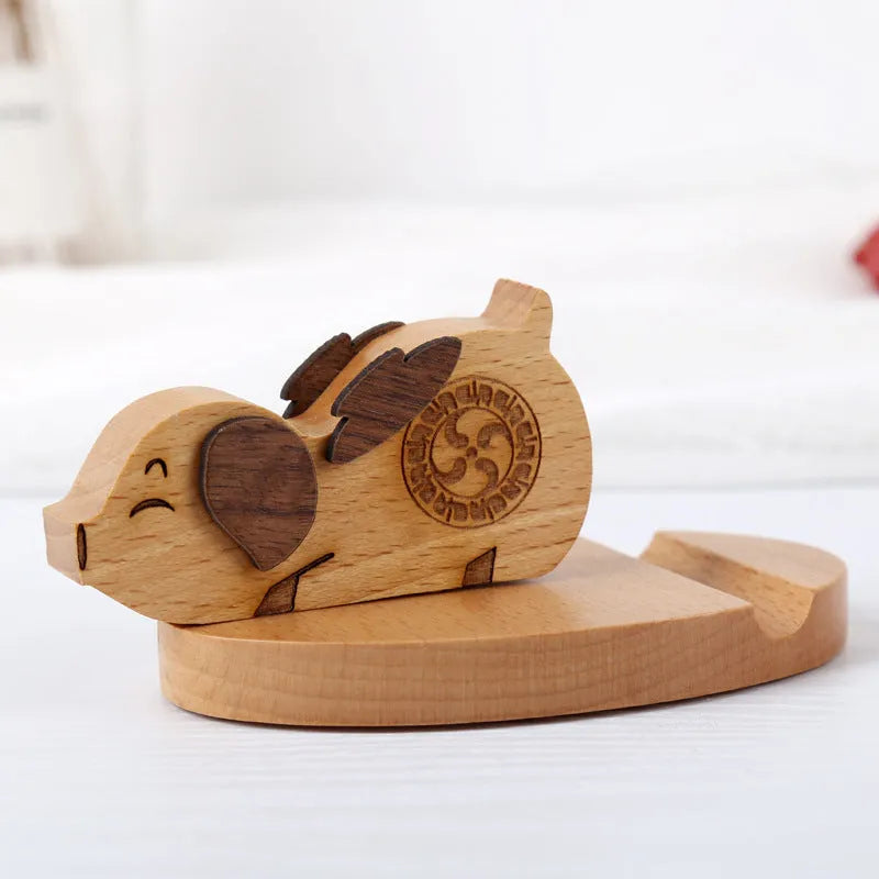 Sculpted beech wood lazy bracket phone holder with custom engraved text on a wooden desk.