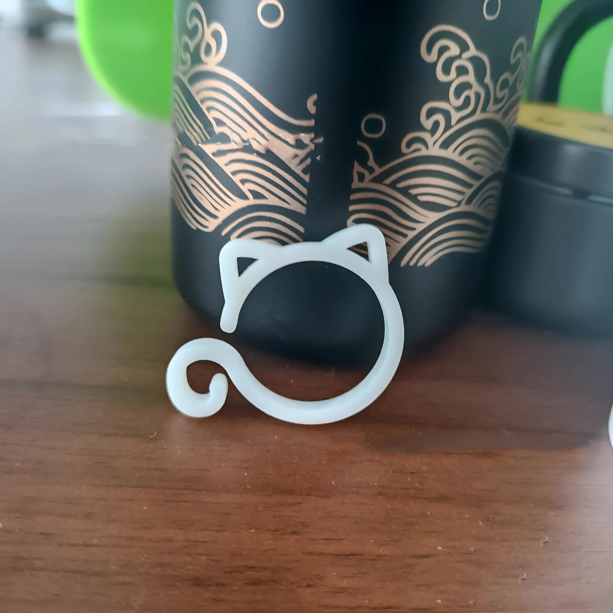 A colourful cat-shaped plastic clip for securing plant stems in the garden.
