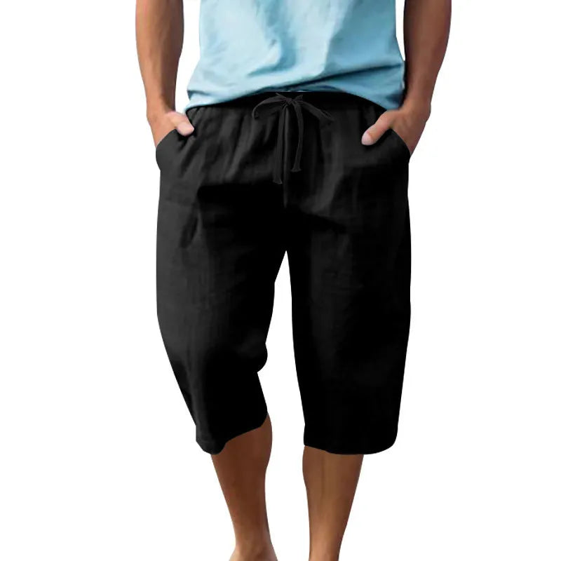 Man wearing loose-fit, solid-colour linen shorts in a light blue shade, showing the cropped length and drawstring waist.