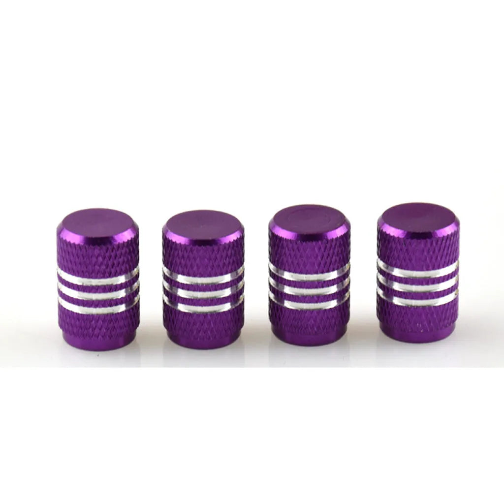 Set of coloured aluminium alloy tyre valve caps for car wheels on a grey background.