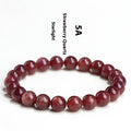Cherry red strawberry quartz crystal bracelet with geometric beads on a wrist.