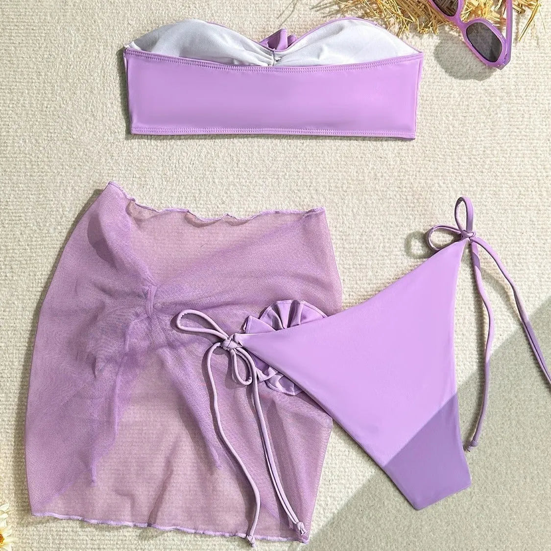 Blue women's swimsuit set with 3D flower, bikini bottoms, and a separate wrap skirt laid flat.